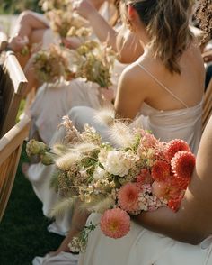 the bridesmaids are sitting down with their bouquets