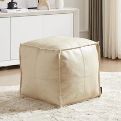 a large square ottoman sitting on top of a white rug in front of a window