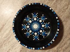 a black plate with blue and white dots on it sitting on a counter top next to a tile floor