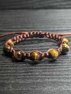 Beautiful high-quality natural yellow/brown 10mm Tigers Eye gemstone macrame bracelet. This piece is assembled with a dark brown satin nylon cord and is finished with a slide-adjustable closure. This beautiful macrame piece would make a great gift!  Tiger's Eye is known for its grounding, protective, and harmonizing properties. It is said to encourage self-confidence, promote mental clarity, and attract abundance and prosperity. Tigers Eye stone is known for its ability to shield against negativ Brown Bracelets With Adjustable Cord And Round Beads, Brown Beaded Bracelet With Adjustable Cord, Brown Adjustable Beaded Bracelets With Round Beads, Brown Beaded Bracelets With Adjustable Cord, Adjustable Brown Beaded Bracelets With Sliding Knot, Adjustable Brown Beaded Bracelets, Brown Hand-strung Friendship Bracelets With Round Beads, Brown Friendship Bracelets With Round Hand-strung Beads, Brown Hand-strung Friendship Bracelets As Gift