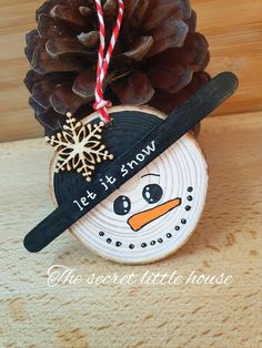 a pine cone with a snowman ornament hanging from it