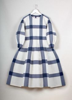 a white and blue checkered dress hanging on a wall