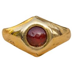 a gold ring with a red stone in it's center, against a white background