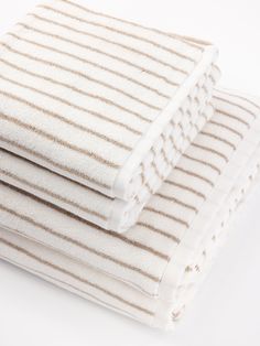 three towels stacked on top of each other in white and brown stripes, folded neatly