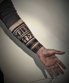 a man's arm with a black and white tattoo design on the left hand