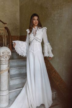 a woman in a white dress standing on some stairs