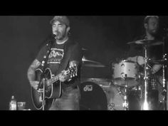 two men are playing guitars and singing into microphones at a music concert in black and white