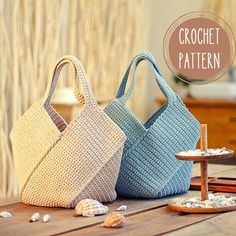 two crochet bags sitting on top of a wooden table next to seashells