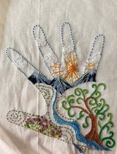 a close up of a piece of cloth with an embroidered tree and sun on it