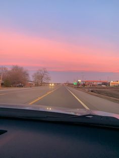 the sun is setting on an empty road