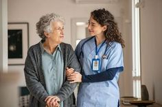 two women in scrubs are talking to each other while standing next to each other