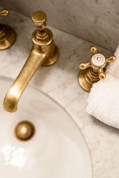 a bathroom sink with gold faucet and white towels