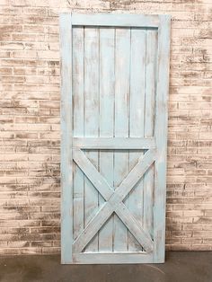 an old blue barn door is shown against a brick wall