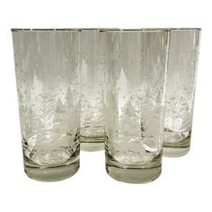 four clear glass tumblers are lined up on a white background, one is empty