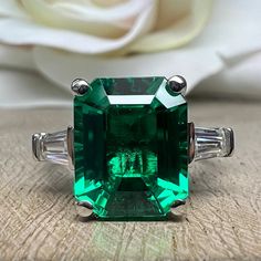 "The ring pictured is lab created emerald with moissanite accents #6725 for emerald earrings click here: https://etsy.me/3AN4nqW for emerald rings click here: https://etsy.me/3JIov0a for emerald pendants click here: https://etsy.me/3Td2gnv -Approximate total carat weight: 5.50ctw diamond equivalent -Center Stone Size: 11x9mm - approx. 5.00ct diamond equivalent -Center Stone Shape: Emerald Cut -Gem Type: Lab Created Emerald -Stone Clarity: VS2 -Stone Color: Deep Green Eye-Clean -Moh's Scale: 8.5 Gia Certified Baguette Cut Emerald Ring For May Birthstone, Green Emerald Ring With Baguette Diamonds For May Birthstone, Baguette Cut Emerald Ring For May Birthstone, May Birthstone Emerald Ring With Baguette Diamonds, Anniversary Green Baguette Diamond Ring, Moissanite Emerald Ring Baguette Cut Gift, Gift Emerald Moissanite Ring Baguette Cut, Gift Moissanite Emerald Ring Baguette Cut, Green Moissanite Baguette Cut Diamond Ring