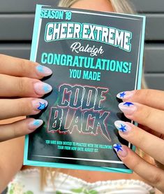 a woman holding up a congratulations card with blue and white nail art on it's nails