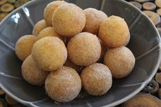 a bowl filled with sugar covered donuts on top of a table