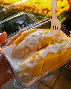 a person holding a plastic fork and some food in a container with lemons on it