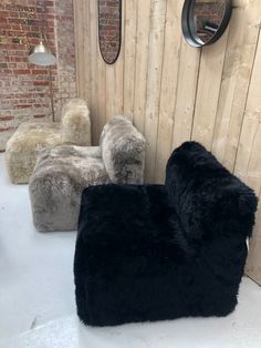 two black sheepskin bean bags sitting next to each other in front of a wooden wall