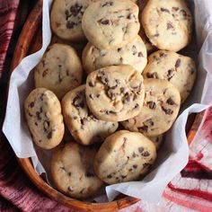 chocolate chip cookies in a wooden bowl on a red and white towel