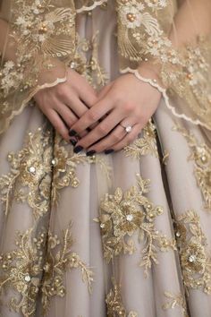 a close up of a person's hands wearing a dress with gold flowers on it