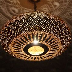 a decorative light hanging from the ceiling in front of a patterned wallpapered background