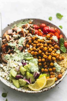 a bowl filled with chickpeas, tomatoes, cucumber and avocado