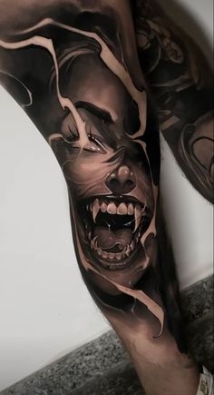 a man's leg with tattoos on it and an evil clown face in the middle