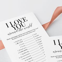 i love you around the world game cards with pink ribbon on white paper and matching envelope