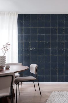 a dining room table with chairs and a vase on it next to a blue tiled wall