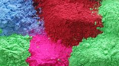 there are many different colored powders on the table and one is red, green, blue, and purple