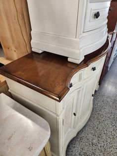 a white cabinet with wood top and drawers in a room filled with other furniture items