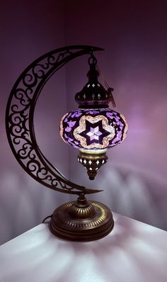 a purple lamp sitting on top of a table next to a moon shaped light fixture