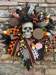 a halloween wreath with a skull and candy lollipops in the center on a brick wall