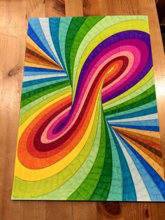 a multicolored piece of art sitting on top of a wooden table