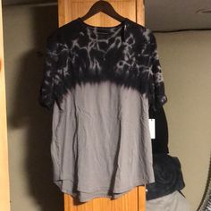 a black and grey shirt hanging on a wooden hanger in front of a door