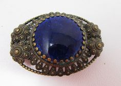 Gorgeous large-size oval brooch with round Lapis or Lapis-like stone. Check out the amazing detail. Marked: Czechoslovakia. Measures 2 1/2 inches wide by 2 inches tall. Has a very sturdy safety pin style clasp. Condition is excellent, with little to no signs of wear. The perfect gift. Blue Oval Brooch For Gifts, Blue Oval Brooch, Blue Oval Brooch For Formal Occasions, Antique Handmade Blue Brooches, Czech Jewelry, Brass Art, Blue Lapis, Vintage Brooch, Safety Pin