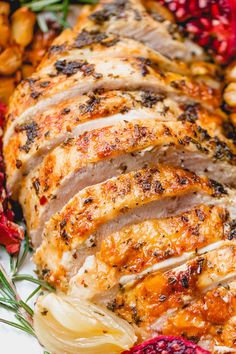 sliced pork with cranberry sauce and onions on a plate next to pomegranates