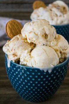 two blue bowls filled with ice cream on top of a wooden table next to cookies