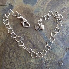 She will definitely be feeling the love with this charming bracelet!  Sterling silver hearts link together to form a delicate chain bracelet.   Finished with a sturdy heart-shaped lobster clasp and a dangling duo of charms.  This comes in two lengths: 8 in. and 8 1/2 in..  The clasp can attach to any of the links to fine-tune the fit.  Made with love, of course! Everyday Sterling Silver Chain Bracelet With Charms, Silver Heart Charm Bracelet For Friendship, Dainty Sterling Silver Charm Bracelet With Heart Charm, Metal Charm Bracelet With Heart Charm For Mother's Day, Sterling Silver Heart Bracelet With Charms, Sterling Silver Bracelet With Heart Charm, Silver Dainty Charms With Lobster Clasp, Sterling Silver Charms Bracelet For Everyday, Silver Sterling Silver Bracelet With Heart Charm