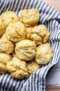 a bowl full of biscuits sitting on top of a wooden table next to a blue and white towel