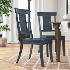 two blue chairs sitting on top of a wooden floor next to a dining room table