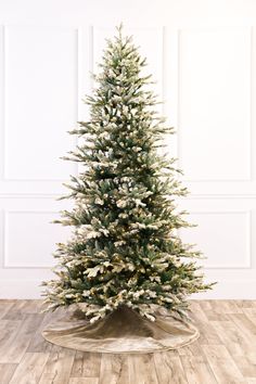 a white christmas tree with snow on the top is in a room that has wooden floors