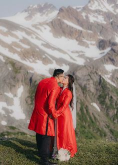 A stunning photo idea is for the bride and groom, both dressed in red, sharing a kiss surrounded by towering snowy mountains, with the vast, serene landscape enhancing the passion and beauty of the moment.| Image by Pala Kovacs