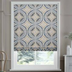 a window with a blue and white patterned roman blind in front of a window sill