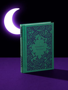 a green book sitting on top of a purple table next to a half - moon