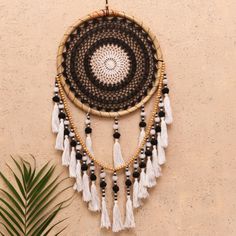 a black and white dream catcher hanging on a wall next to a palm tree in front of a stucco wall