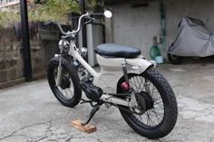 a white motorcycle parked in front of a building with a black seat on the back