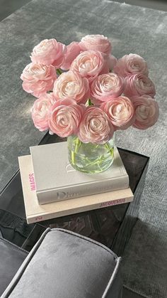 a vase filled with pink roses sitting on top of a table next to a book