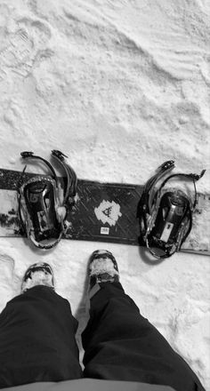 two snowboarders are standing on the snow with their feet propped up in front of them